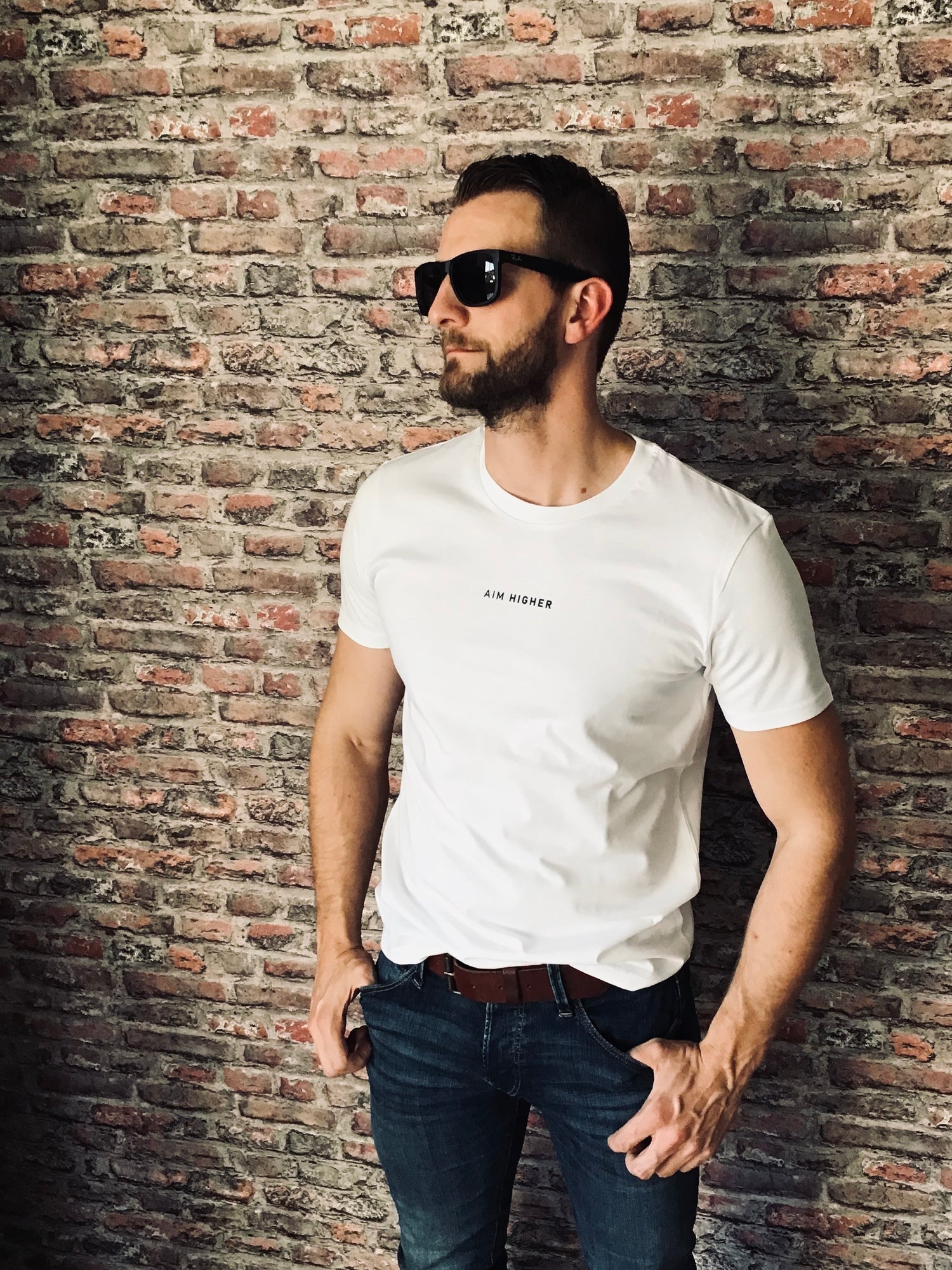 Unisex T-Shirt in der Farbe Weiß mit dem Print "AIM HIGHER". Super lässige Streetwear. Für Sie und Ihn.